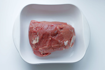 meat, in a white glass plate. Ingredient, fresh meat to cook. Veins, piece, texture of meat. Prices for natural, agricultural and imported products are growing. Meat on a plate