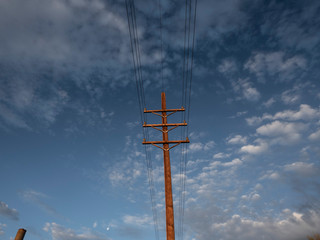 Upward view of a power pole with summer clouds