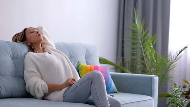 relaxed woman sitting on a sofa in the living room and picks up his smart phone. rest at home after a working day. stock footage video. Close up. home lazy concept