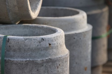 A close up of gray, big cement pipes stored outside on a construction site.