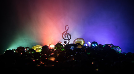 Musical symbol treble clef stainless steel miniature with colorful toned light on foggy background. Selective focus