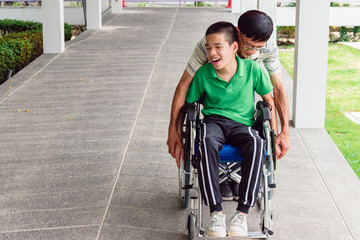 Asian special child on wheelchair wear green shirt learn how to use wheelchair on ramp for disabled people by trainer, Lifestyle in the education age of disability children, Physical Therapy concept.