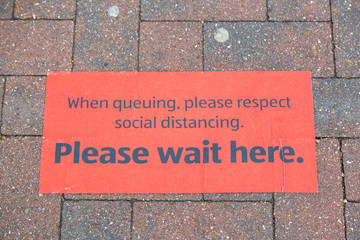 A sign on the ground outside a supermarket showing customers where to queue to conform to social distancing guidelines