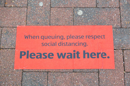 A Sign On The Ground Outside A Supermarket Showing Customers Where To Queue To Conform To Social Distancing Guidelines