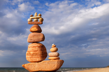 Fototapeta na wymiar Rock zen pyramid of colorful pebbles on a beach on the background of the sea.
