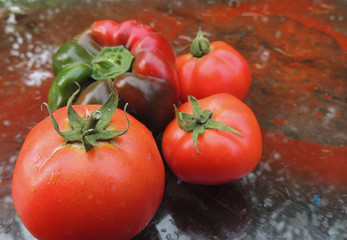 red ripe tomatoes on a wet glass table.