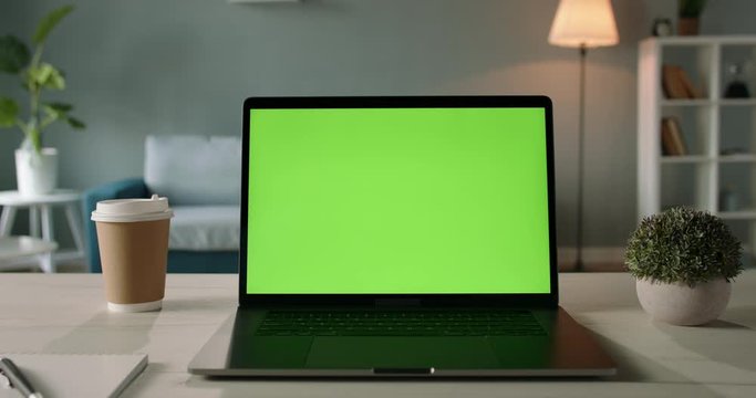 Modern laptop with mock up chroma key green screen st on desk of living room. The only template you need - remote work concept close up 4k video