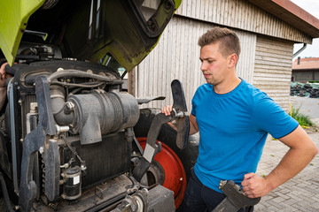 Landwirtschaft und Landtechnik, junger Landwirt vor geöffneter Motorhaube eines Traktors © Countrypixel