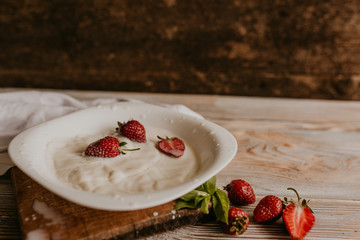 scattered juicy fresh red strawberries on the table with vintage plank. mint leaf. drops and splashes of spilled milk. vegetable cutting board. High quality photo