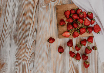 scattered juicy fresh red strawberries on the table with vintage plank. mint leaf. drops and splashes of spilled milk. vegetable cutting board. High quality photo