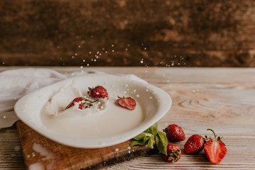 scattered juicy fresh red strawberries on the table with vintage plank. mint leaf. drops and splashes of spilled milk. vegetable cutting board. High quality photo
