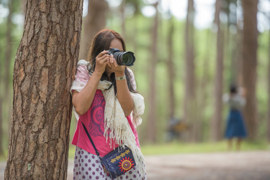 Young Asian tourist woman taking a picture outdoor in the park.