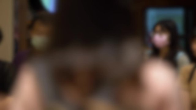 4K, Blurred defocused view of people stand queue with medical masks, long line for eat in a restaurant as store has implemented social distancing measures during the COVID-19 pandemic. Unfocused -Dan