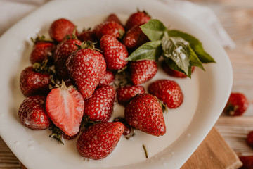 scattered juicy fresh red strawberries on the table with vintage plank. mint leaf. drops and splashes of spilled milk. vegetable cutting board. High quality photo