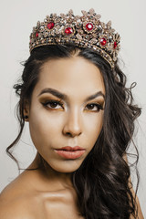 Selective focus shot of a Hispanic female with glamorous makeup and a crown