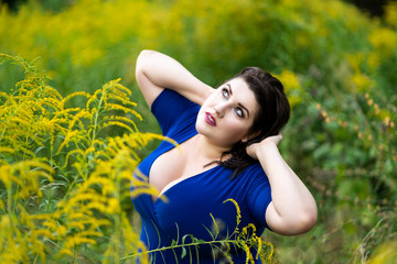 Sexy plus size fashion model in blue dress with a deep neckline outdoors, beautiful fat woman with big breasts in nature