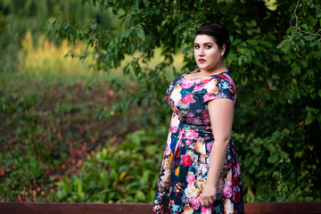 Fototapeta premium Plus size fashion model in floral dress outdoors, beautiful fat woman with big breasts in nature