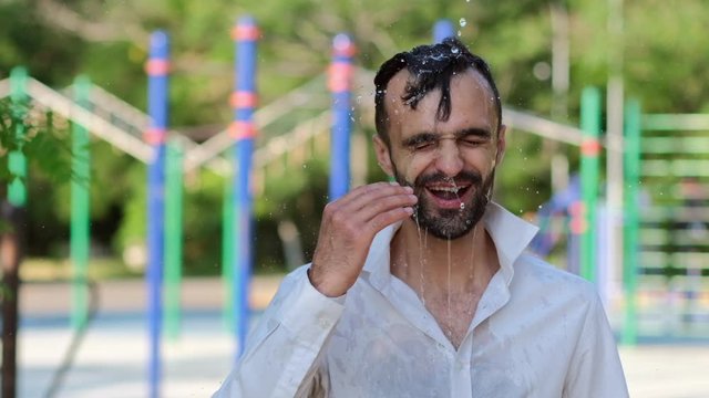 Water pours on the man's head from above, he straightens wet facial hair with his hand. Slow motion at 120 fps. 