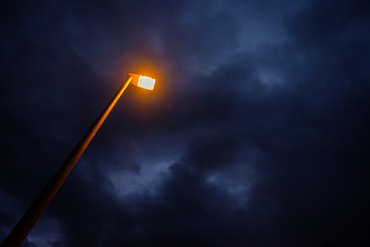 Yellow light of street lamp with cloudy sky