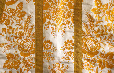 white fabric with gold floral ornaments, like the clothes of a bishop or a pope - yellow background...