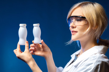 Bio milk food. Two bottles of yogurt in hands of laboratory assistant. Woman medic holds bottles of...