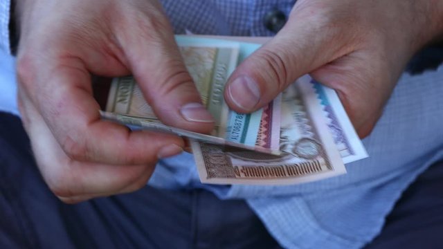 A man in a business shirt counting Mongolia money called Tugrik. Various banknotes