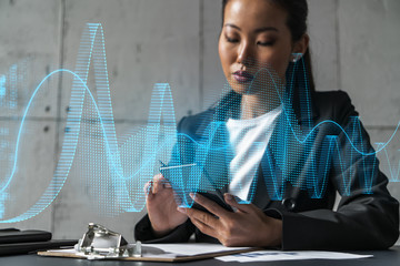 Businesswoman typing phone, work in modern office on new project. Financial graph hologram. Double...