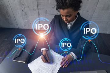 A woman signs contract and ipo symbol hologram. Concept of initial primary offering. Multiexposure....