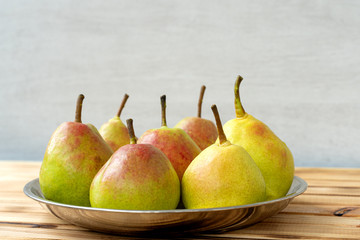 juicy delicious pears in a plate on a wooden background.