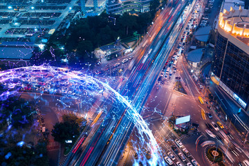 Abstract technology icons hologram on aerial top view of road, busy urban traffic highway at night. Junction network of transportation infrastructure. The concept of hi-tech in logistics.