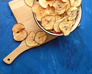 Organic Apple and pear chips (slices) on blue background. Dried Apple and pear slices are a healthy vegetarian fruit snack or cooking ingredient. Healthy food concept. Copy space