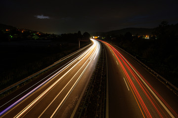Highway in night with light rails of cars and trucks
