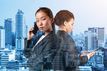 Two young attractive business woman in suits working on project together to gain new career opportunities. Concept of multinational corporate team in Bangkok. Double exposure.