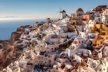 Evening sunlight illuminates the buildings of Oia in Santorini, Greece.