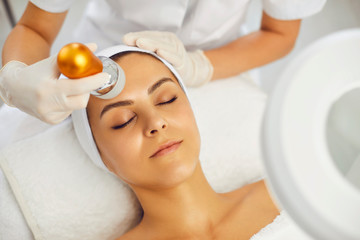 Cosmetologist making facial treatment procedure for woman with cpsmetology equipment.