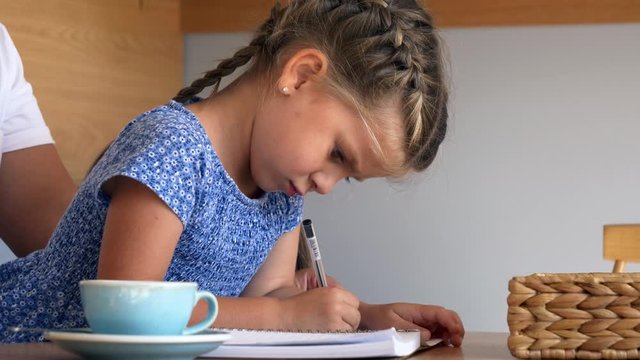little girl draws in a notebook in a cafe