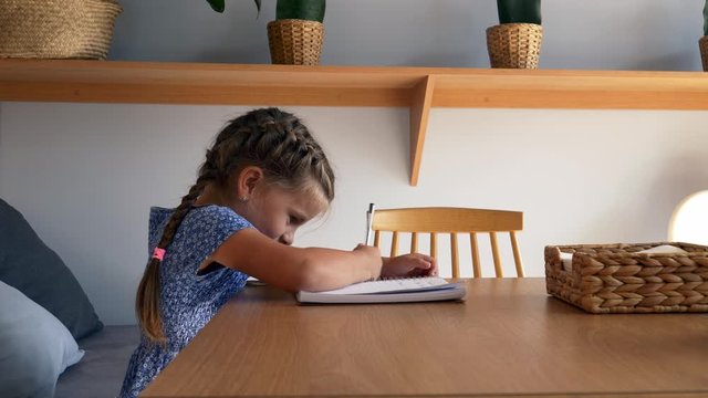 little girl draws in a notebook in a cafe