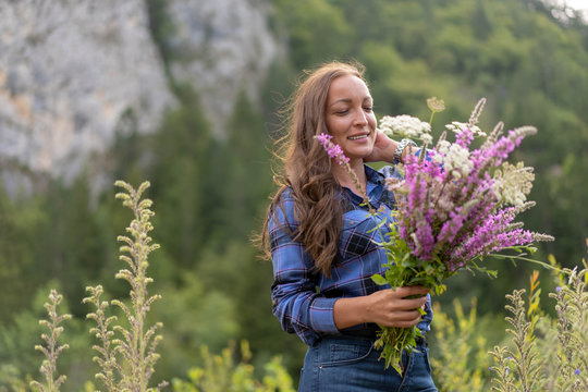 Brunette woman holding bouquet of wild flowers that she just picked up.