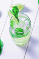 High glass of a drink with lime, ice cubes and mint for the summer