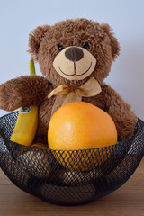 Sweet teddy bear and grapefruit width banana in black basket. - obrazy, fototapety, plakaty