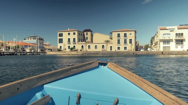 vue d'un batiment r&eacute;nov&eacute; &agrave; Marseillan village sur la cote, depuis une barque qui avance sur la lagune de Thau.