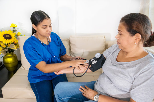 Hispanic Woman Doctor Uses Blood Pressure Check And Consults Woman Patient