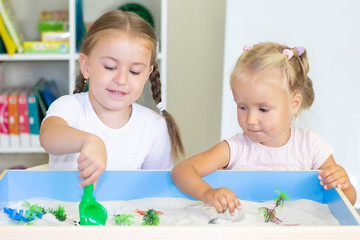Fototapeta premium girls playing in the sand, educational activity with a child