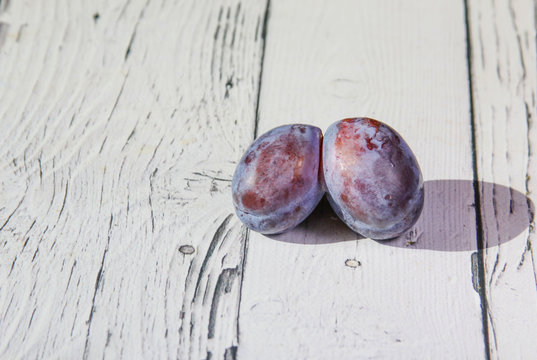 Trendy ugly organic fruit purple plum on the wooden background. Funny, deformed, unnormal fruit or food waste concept. Horizontal orientation. 