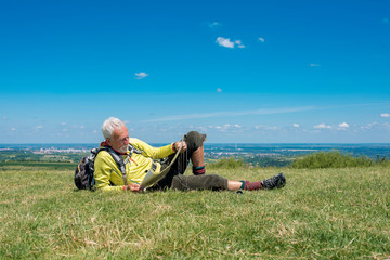 Naklejka na ściany i meble Caucasian senior man hiker taking a break in nature and checking topographic map 