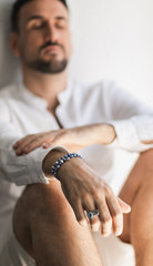 Young white man with a beard and casual shirt wearing a blue sapphire bracelet.