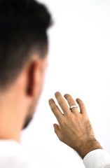 White man looks at his hand with a ring placed on his finger. Jewelry for men. Engagement ring.