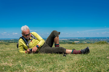 Naklejka na ściany i meble Active senior man, hiker, taking a break in the nature while checking coordinates with hand held GPS navigator device