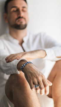 Young white man with a beard and casual shirt wearing a blue sapphire bracelet.