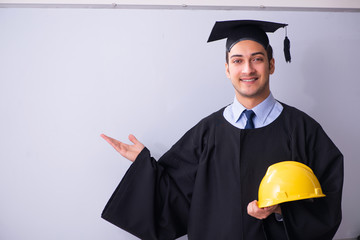 Young male graduate in front of board